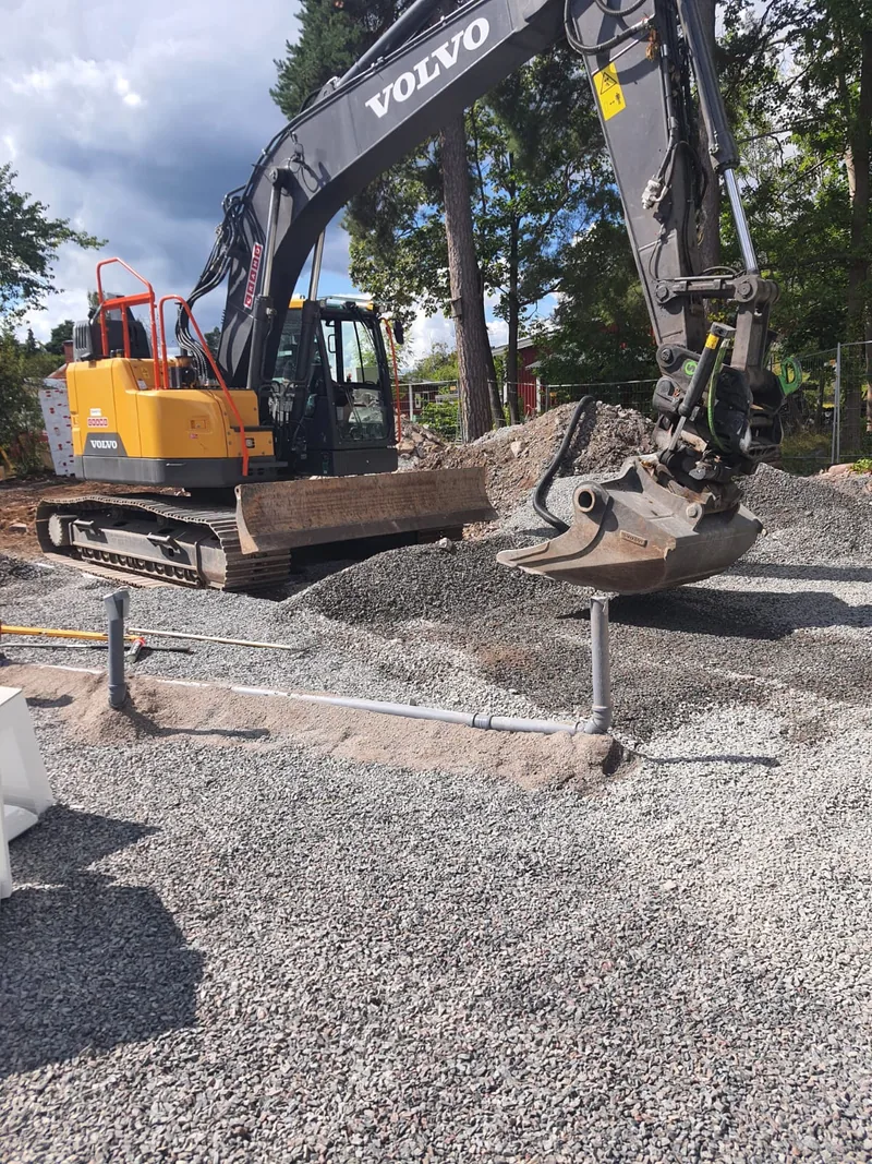 Grävmaskin utför markarbeten med rörläggning på byggarbetsplats